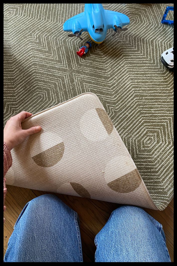 Photo of the author holding the corner of her Totter and Tumble play mat to reveal both sides and patterns.