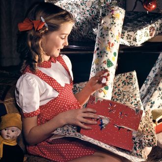 Girl with presents underneath Christmas tree.