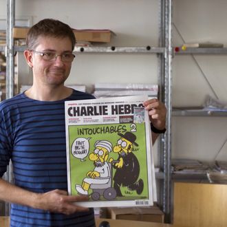 French satirical weekly Charlie Hebdo's publisher, known only as Charb, presents to journalists, on September 19, 2012 in Paris, at the headquarters, the last issue which features on the front cover a satirical drawing titled 