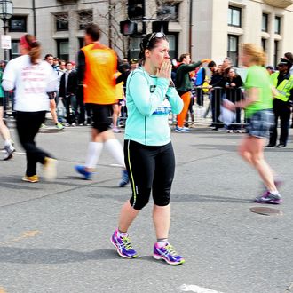 BOSTON, MA - APRIL 15: A woman looks on as runners pass near Kenmore Square after two bombs exploded during the 117th Boston Marathon on April 15, 2013 in Boston, Massachusetts. Two people are confirmed dead and at least 28 injured after at least two explosions went off near the finish line to the marathon. (Photo by Alex Trautwig/Getty Images)