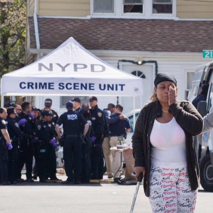 An unidentified woman wipes her face after talking with police officers Sunday, May 3, 2015 about the shooting of a police officer in the Queens borough of New York. Demetrius Blackwell is accused of shooting a New York City police officer in the head Saturday evening and is being charged with two counts of attempted murder of a police officer. (AP Photo/Mark Lennihan)