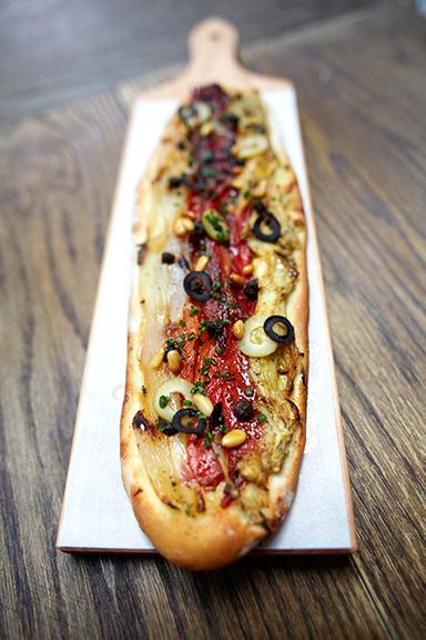 Flatbread with escalibada, black olives, and pine nuts