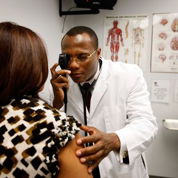 POMPANO BEACH, FL - APRIL 20: Emlyn Louis, MD speaks with Julia Herrera as he examines her at the Broward Community & Family Health Center on April 20, 2009 in Pompano Beach, Florida. Mr. Louis's job was saved when the American Recovery and Reinvestment Act provided funds for community health centers. The Broward Community & Family Health Centers received nearly $1.5 million in Recovery Act funds, allowing them to halt layoffs and instead hire 13 additional employees. In total, the funds will provide services for an additional 6,600 underserved South Floridians while saving or creating 15 local jobs. (Photo by Joe Raedle/Getty Images) *** Local Caption *** Emlyn Louis;Julia Herrera