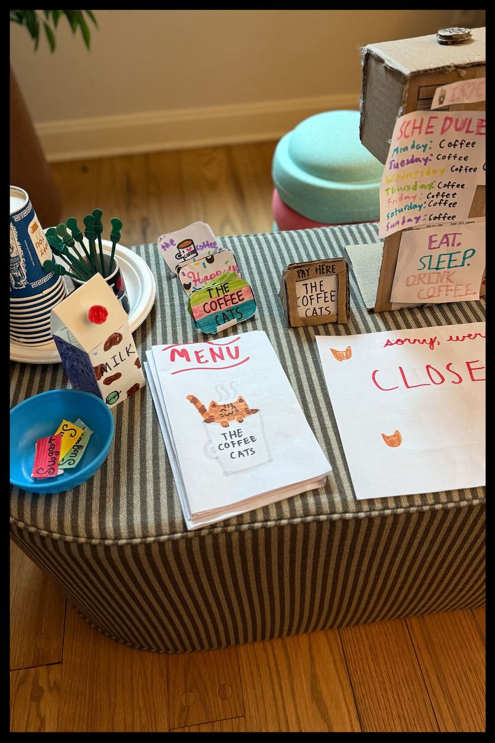 A kid's pretend coffee shop set up on a striped pill-shaped fabric coffee table.