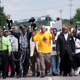 Protesters fill Florissant Road in downtown Ferguson, Mo. Monday, Aug. 11, 2014, marching along the closed street. The rally marched along the street in front of the town's police headquarters to protest the shooting of 18-year-old Michael Brown by Ferguson police officers on Saturday. (AP Photo/Sid Hastings)