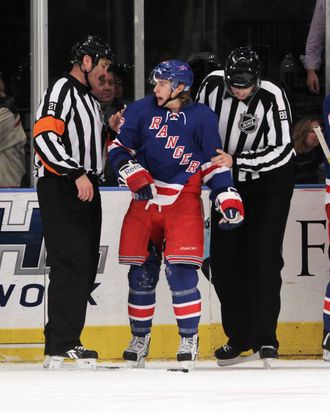 Referee Don Van Massenhoven #21 and linesman Mike Cvik #88 escort Carl Hagelin #62 of the New York Rangers to the penalty box after his first period charging penalty against the Dallas Stars at Madison Square Garden on December 13, 2011.