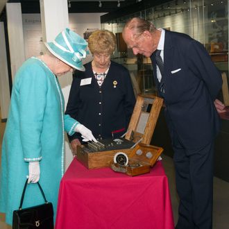 MILTON KEYNES, UNITED KINGDOM - JULY 15: Queen Elizabeth II presses the button to start the enigma code breaking machine as Prince Philip, Duke of Edinburgh and wartime operator Ruth Bourne look on during a visit to Bletchley Park on July 15, 2011 in Milton Keynes, England. Bletchley Park is the historic site of secret British code-breaking activities during WWII. (Photo by Arthur Edwards - WPA Pool/Getty Images)