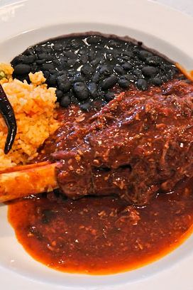 Lamb shank braised in chili pulla, huajes, and epazote, with rice and bean