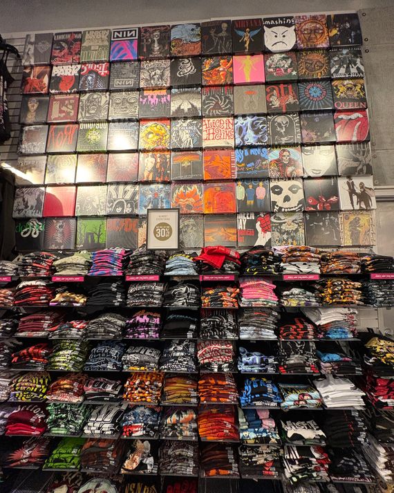 An assortment of band-related graphic tees spanning an entire wall. 