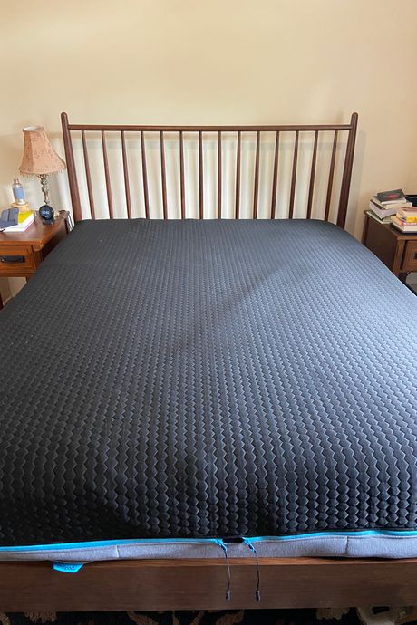 A black mattress cover on a bed.