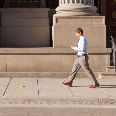 Man texting and walking near a banana peel