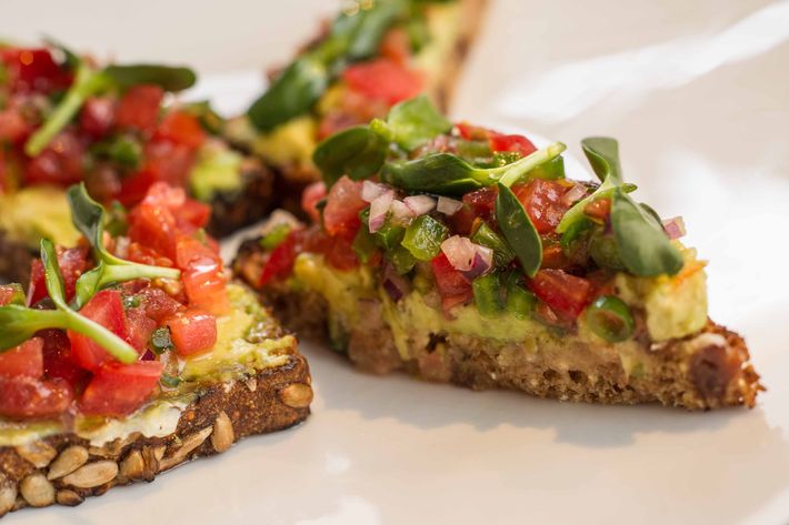 Avocado toast with cumin butter on multigrain bread, sunflower shoots, and pico de gallo.