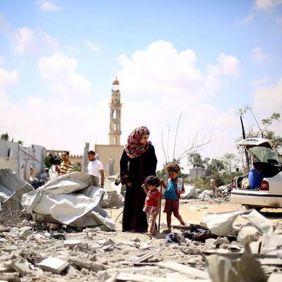 Palestinians walk through the ruins of their buildings during a cease-fire which starts at 10 o'clock in the morning in Beit Lahia, Gaza on August 04, 2014. Palestinians try to collect usable belongings amongst the ruins and held funeral ceremonies of their relatives killed by Israeli strikes, during the truce. 