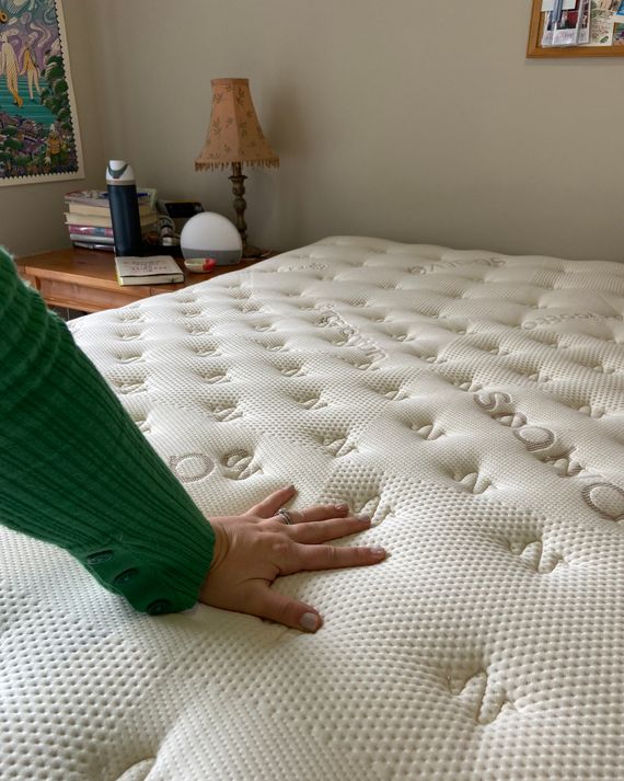 A hand pressing into a tufted mattress top.