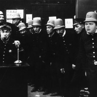 A scene from 'In the Clutches of the Gang', a Keystone Cops silent comedy directed by George Nichols and Mack Sennett. Left to right : Ford Sterling (on phone), Edgar Kennedy, George Jeskey, Al St John, Hank Mann, Rube Miller, and Roscoe Fatty Arbuckle (1887 - 1933). (Photo by Hulton Archive/Getty Images)