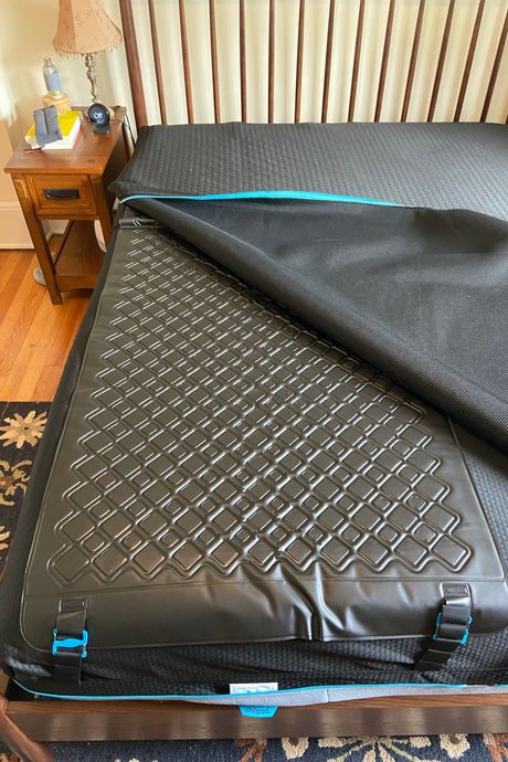 A black mattress cover unzipped to show a plastic hydrolayer.
