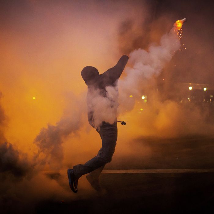 A protester throws a gas canister back at police during clashes at North Ave and Pennsylvania Ave in Baltimore