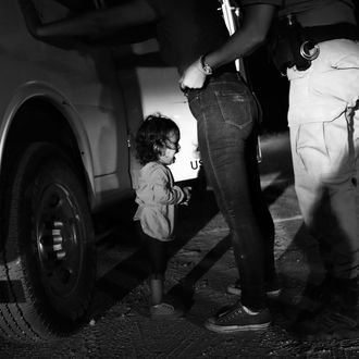 A 2-year-old girl crying as a Border Patrol agent pats down her mother.