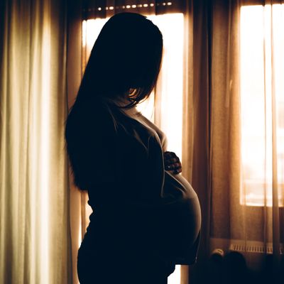 Silhouette of a pregnant woman by the window