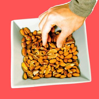 Man reaching for nut in bowl, close-up.