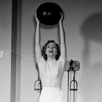 Young woman holding fitness ball in gym