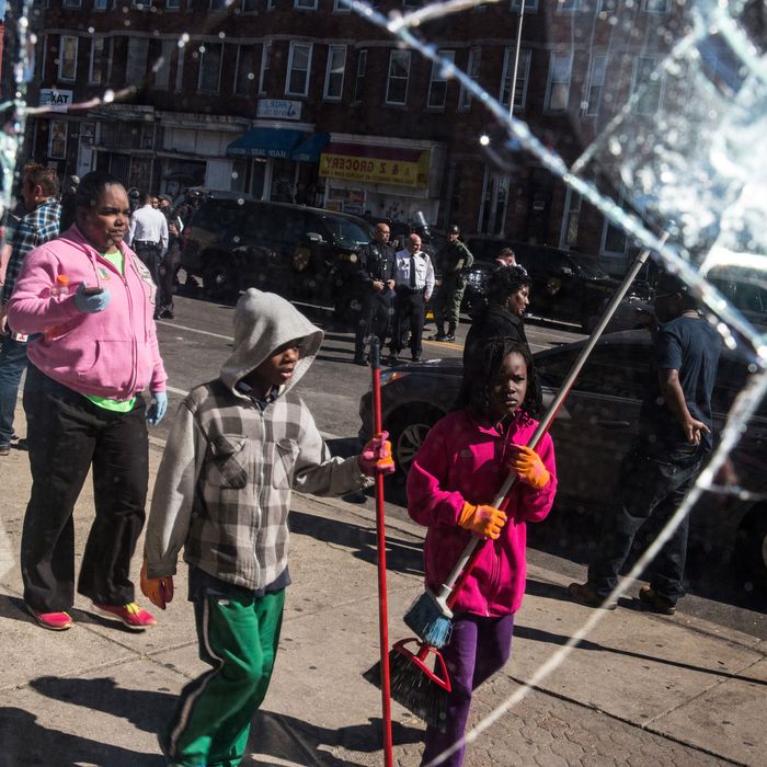 BALTIMORE, MD - APRIL 28: People helping to clean up debris caused by rioting yesterday after the funeral of Freddie Gray are seen in the reflection of a partially destroyed window on April 28, 2015 in Baltimore, Maryland. Gray, 25, was arrested for possessing a switch blade knife April 12 outside the Gilmor Houses housing project on Baltimore's west side. According to his attorney, Gray died a week later in the hospital from a severe spinal cord injury he received while in police custody. (Photo by Andrew Burton/Getty Images)
