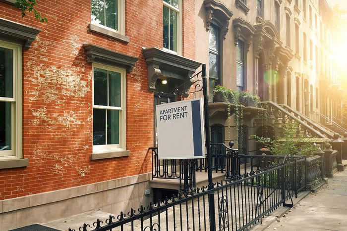 An apartment for rent sign in front of a red brick building