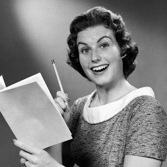 Portrait of woman smiling, holding up pencil & budget book. (Photo by H. Armstrong Roberts/Retrofile/Getty Images)