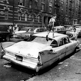 Bronx, New York City, New York / Summer, 1966 On Fox Street in the Bronx, an abandoned Plymouth “Savoy” becomes a jungle gym for kids to play in and on.